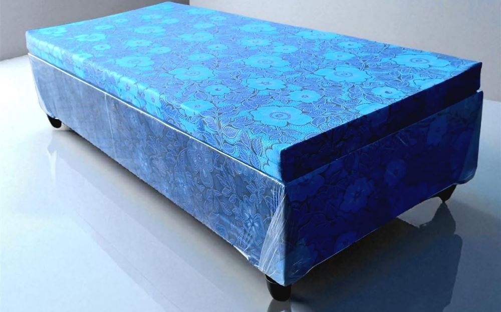 Blue floral-covered 4-inch high density foam single bed on a base with dark legs